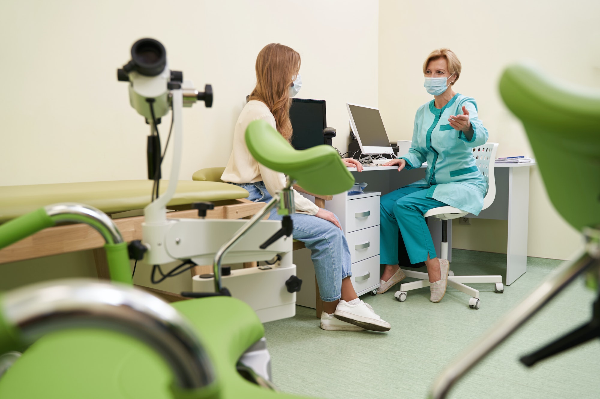 Competent female doctor pointing at gynecological chair