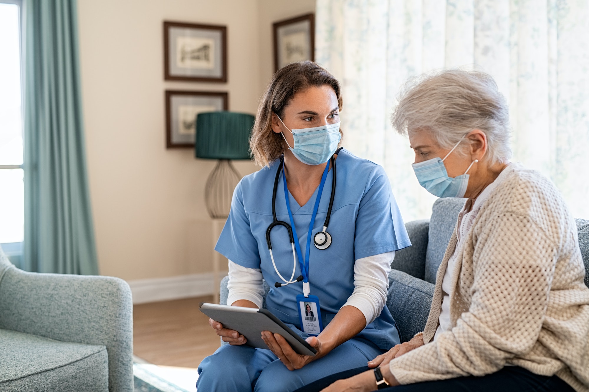 Nurse explaining therapy to senior woman at home visit